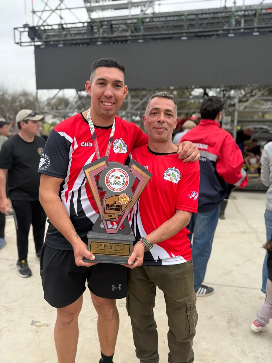 Bomberos con trofeo en competencia de habilidades bomberiles